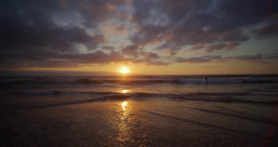 Landscape of a beach with calm waves and the sunrise on the horizon
