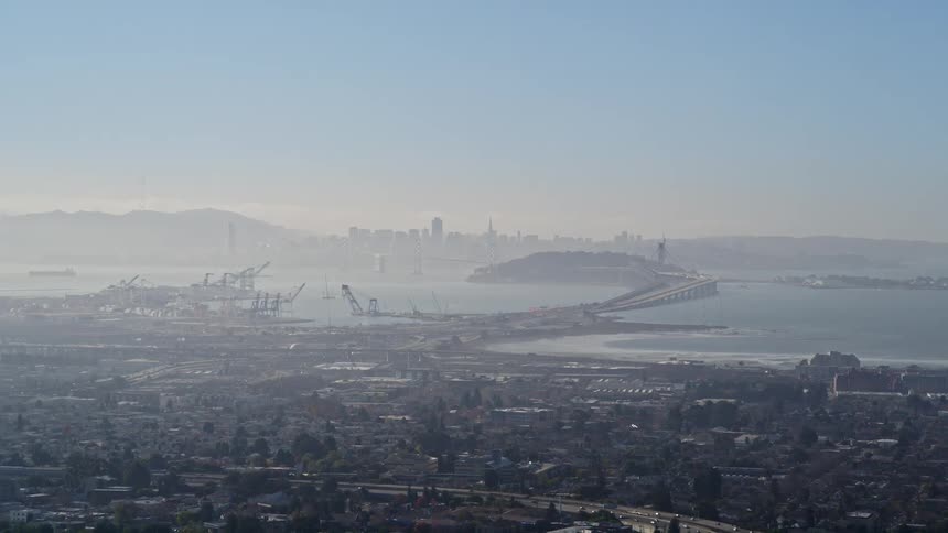 Aerial view of a large harbor near a suburban town connected to a metropolitan city by a highway bridge