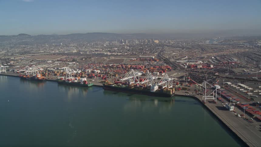 Aerial panorama of cranes on a shipping channel in a port area during a blue sky day