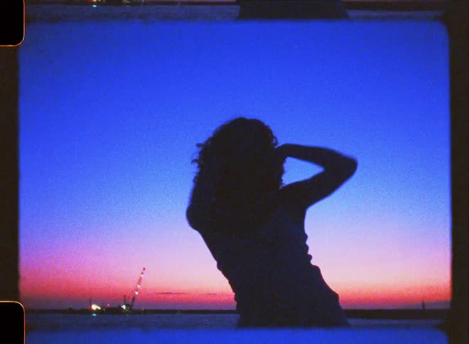 Silhouette of a woman on the beach with the red sky on the horizon dancing