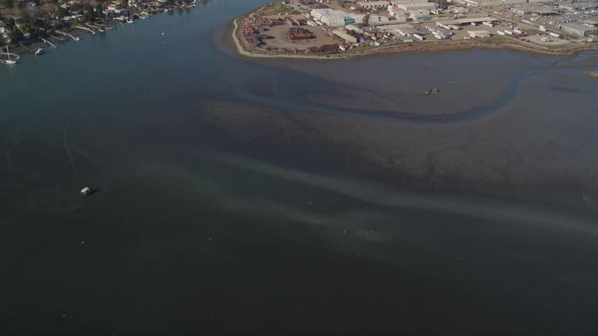 Aerial panorama of a sea in the middle of a city with one side urban and the other a distribution center