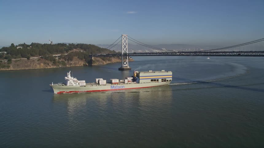 A cargo ship travels under the bridge