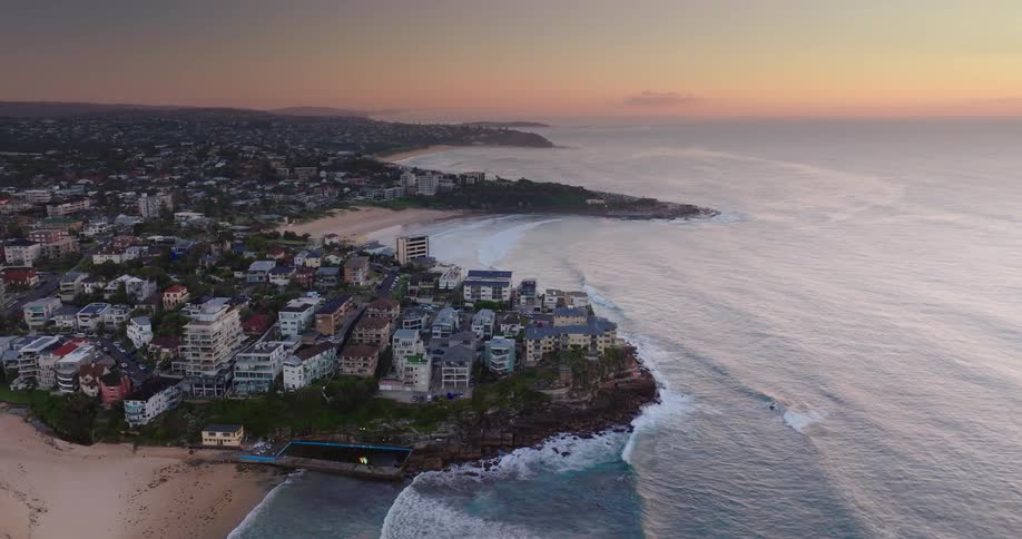 Aerial view of a coastal town with buildings near the beach at sunset