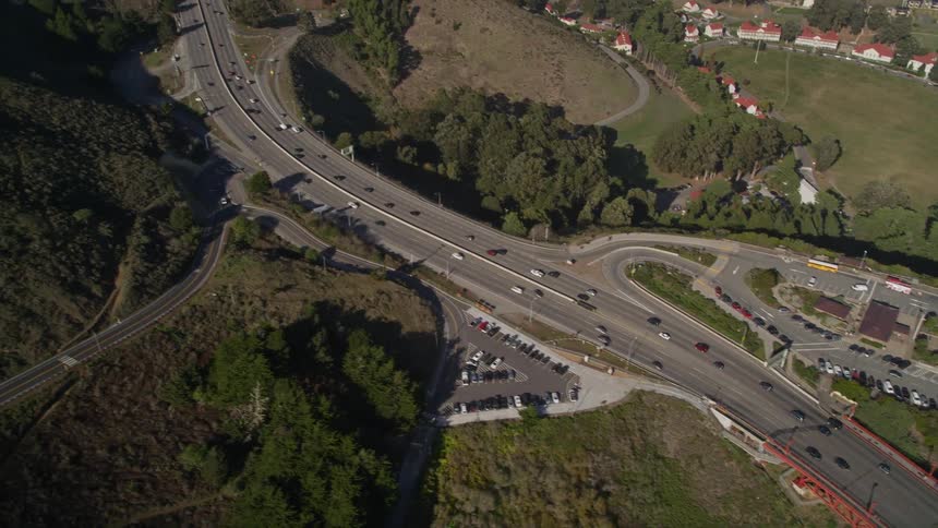 Traffic flows along highway between a mountain and a coastal neighborhood