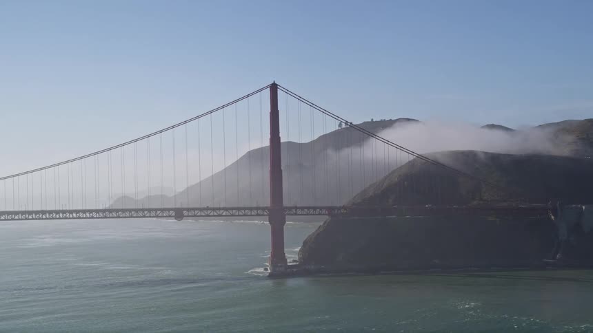Golden gate bridge over the sea and connecting the rocky coast during the day