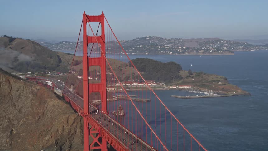 Aerial panorama of the golden gate bridge over the sea with vehicle traffic and an urban city on the horizon
