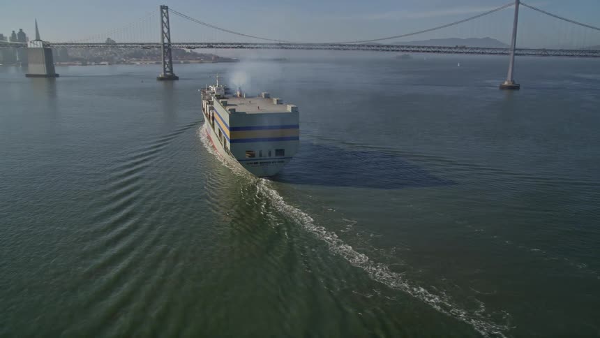 Cargo ship passing through the sea with a metropolis on the horizon