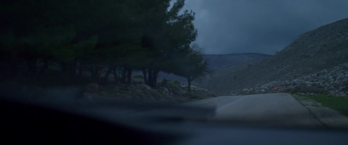 A vehicle travels down a road in the wilderness