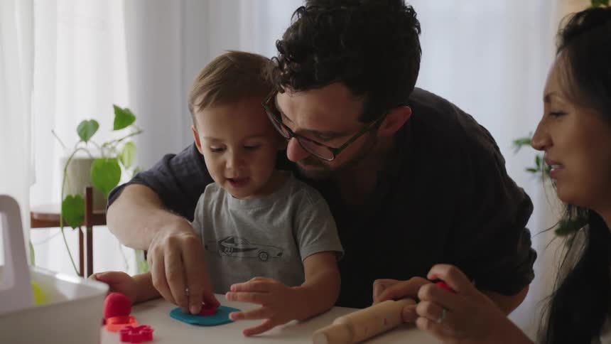Father and mother playing with their son in the living room at home