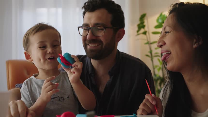 Father and mother with their son playing with modeling clay