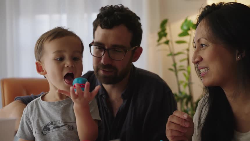 A young child and his parents enjoy a playful moment together smiling and laughing