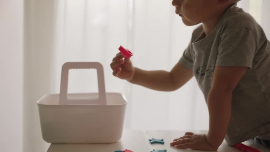 Little boy picking up a toy and giving it to his mother who is next to him