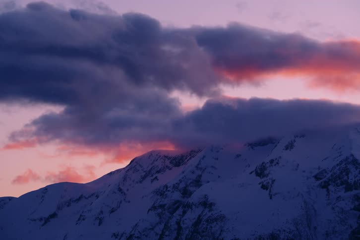 A tall mountain range covered in snow and clouds