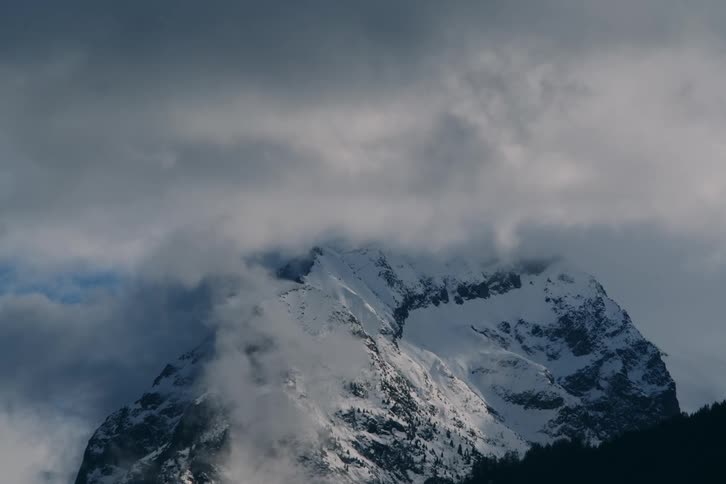 A large mountain covered in snow and clouds