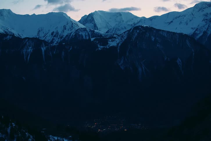 A mountain range with huge snowcapped mountains and a small town at the base