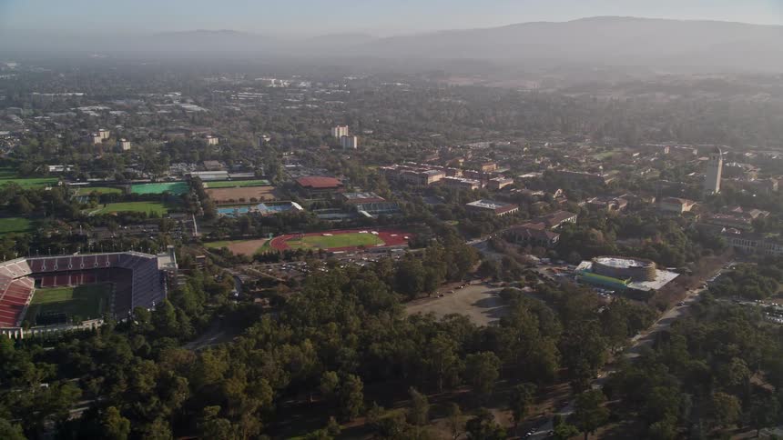 Aerial panorama of an urban city on wooded hills and with sports stadiums around