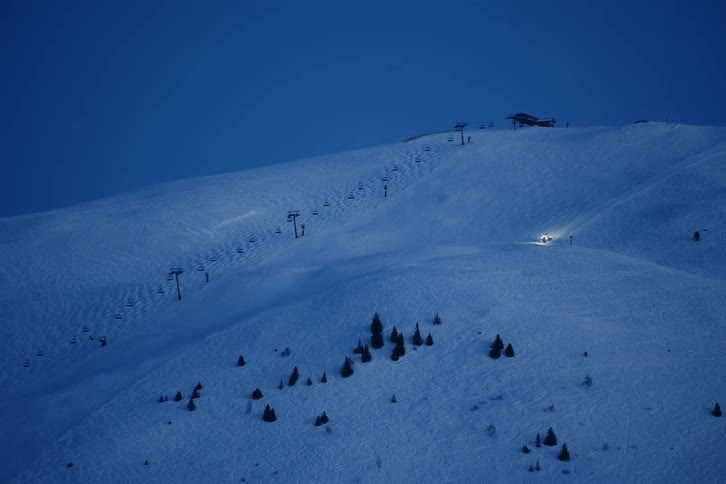 A person drives a piece of equipment on a ski slope