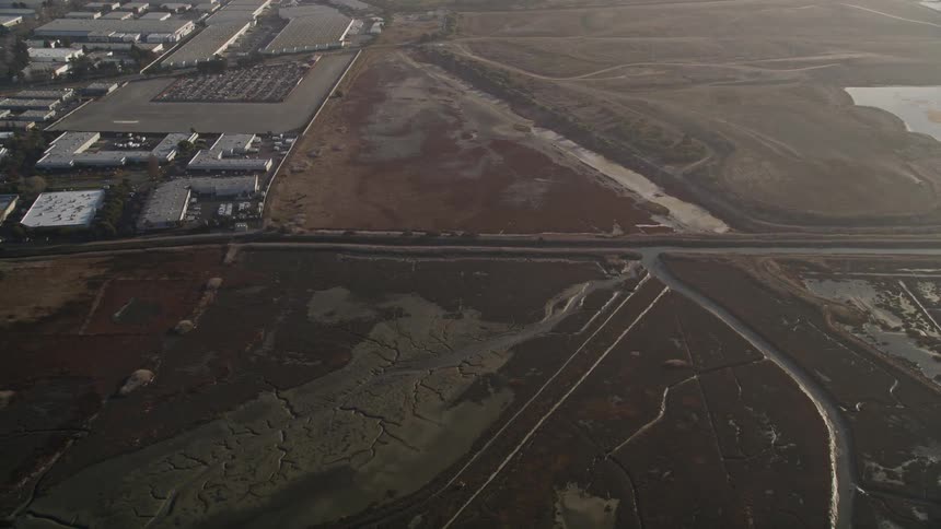 Aerial panorama of a plot of land with canals and a nearby industry