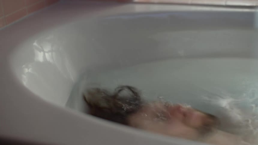 Man lying in a bathtub and becoming submerged