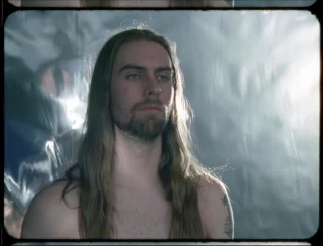A long haired man opens his eyes and smiles
