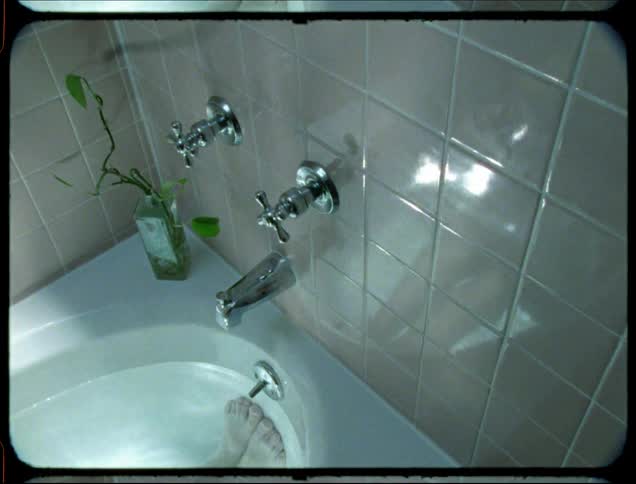 Person soaks in bathtub while light reflected from the water plays across the tiled wall