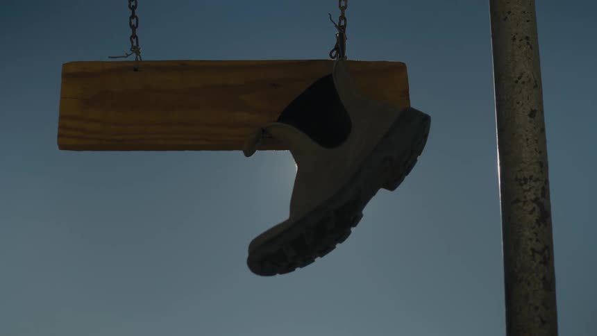 A boot hangs from a wooden sign