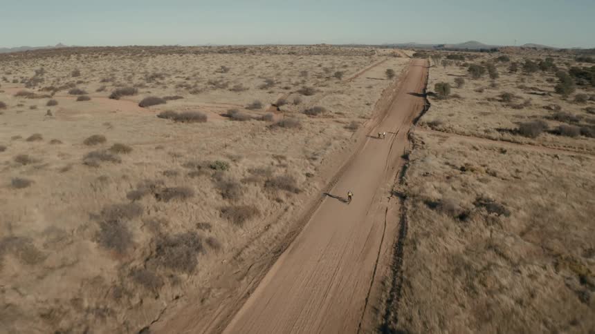 Three cyclists on a sandy street in a desert