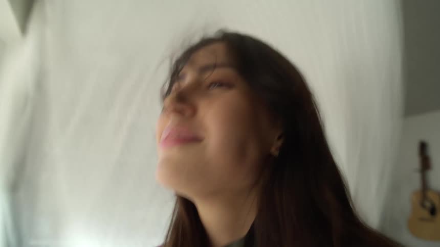 The wind blows the womans hair by the window
