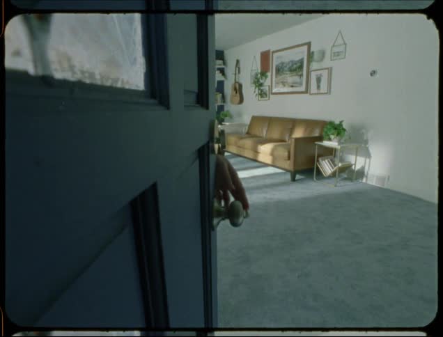 Woman opens front door and leaves house as wind blows curtains on open window