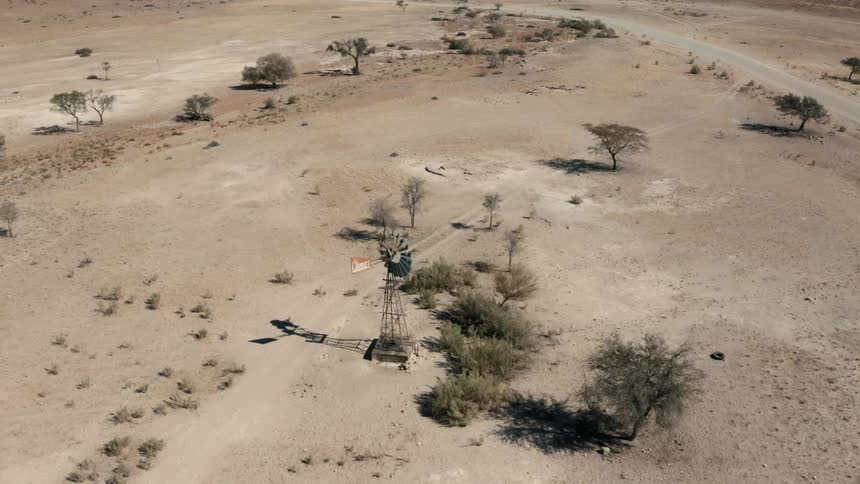 Aerial view of a windmill in the desert surrounded with sparse vegetation