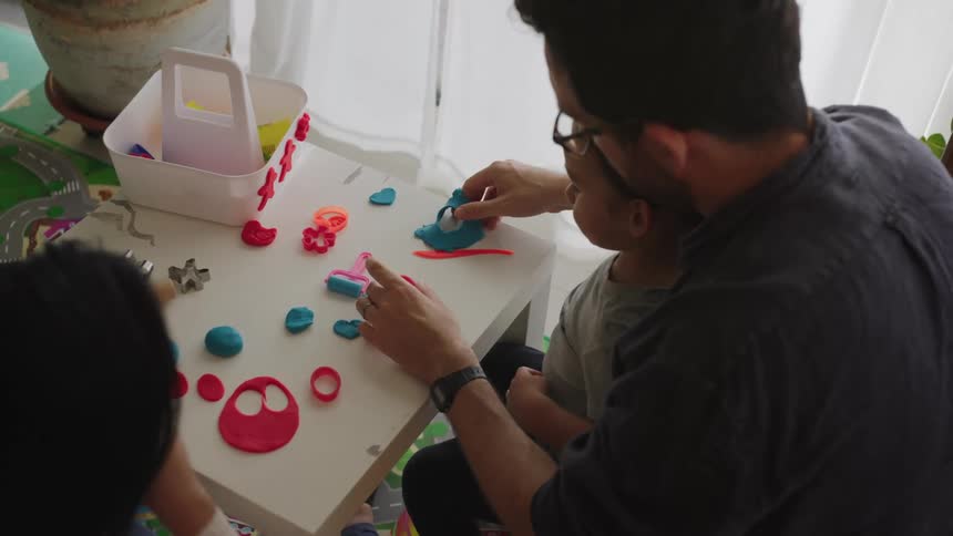Family plays with playdoh while sitting at table in home