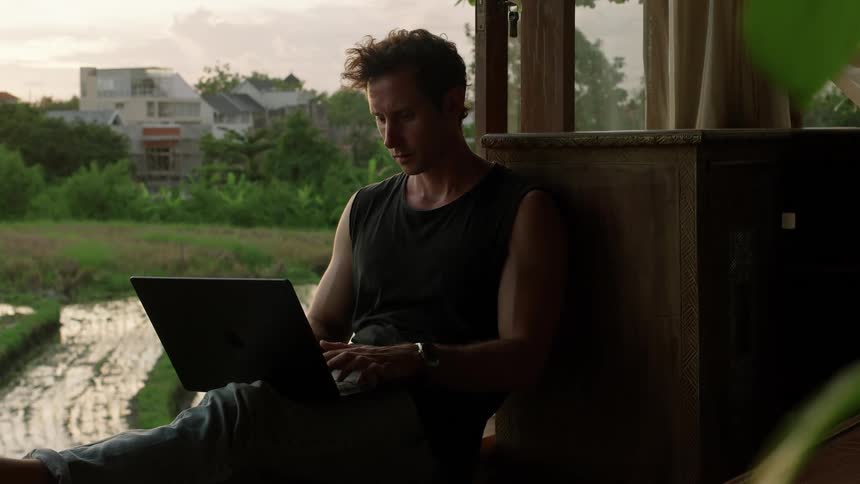 A man is using his laptop on the porch