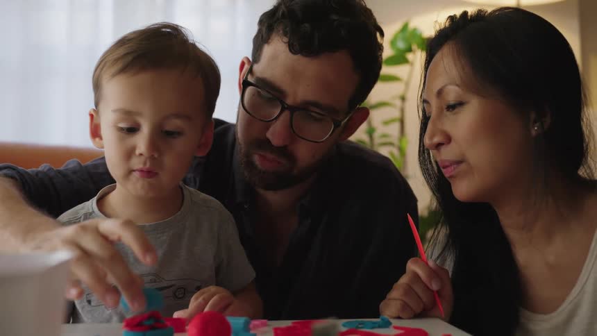 Parents play with their son in a living room