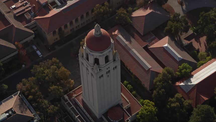An aerial view of a large white tower surrounded by small houses and some trees