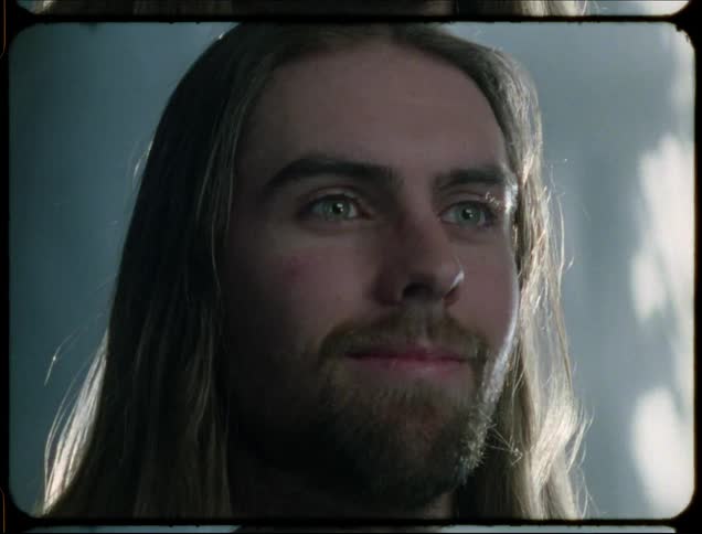 A man opens his eyes and smiles while light reflects around him