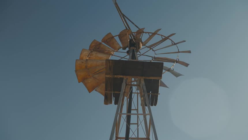 Upward view of a windmill against a cloudless blue sky