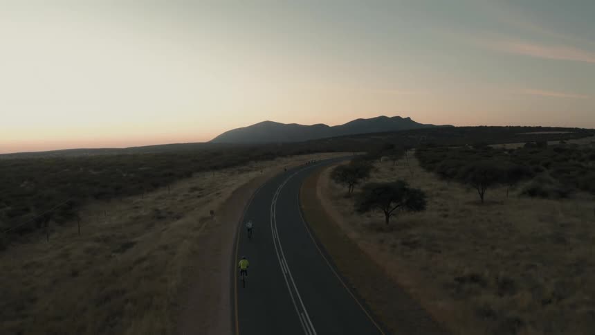 Two people are cycling on the long highway