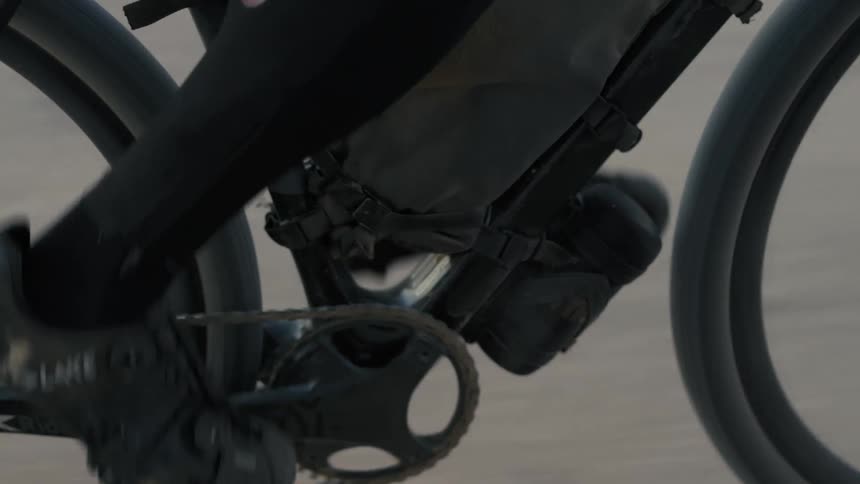 Legs of a person pedaling a bicycle and an outdoor environment