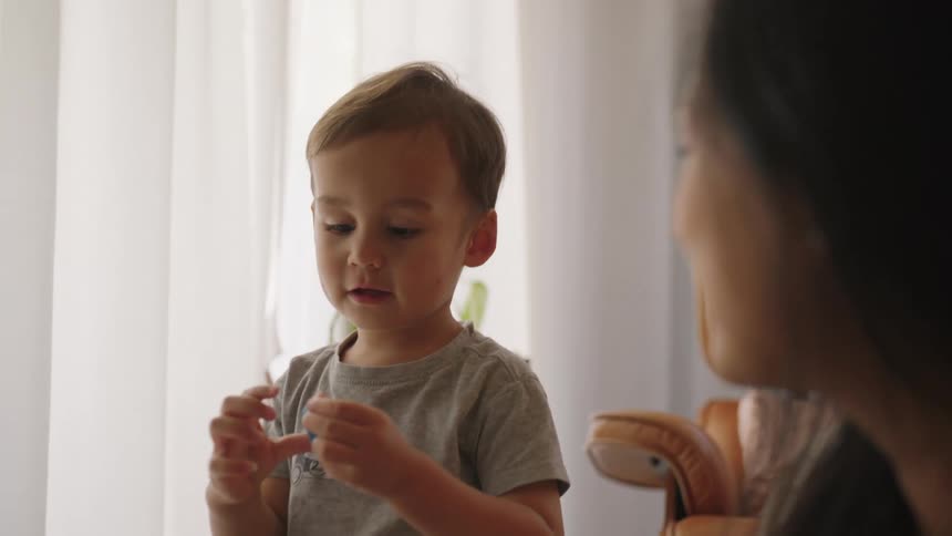 A child playing with a toy next to his mother at home