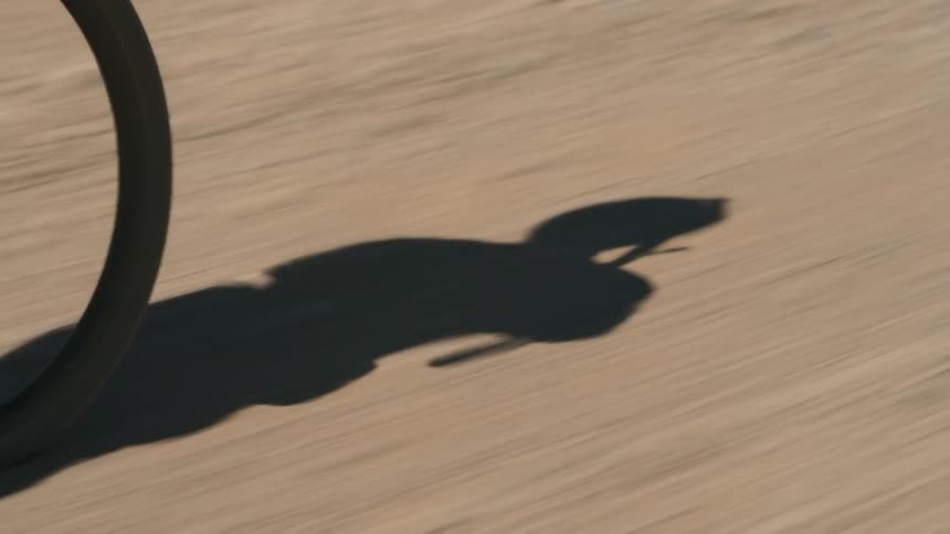 The silhouette of a cyclist as they travel down a gravel road