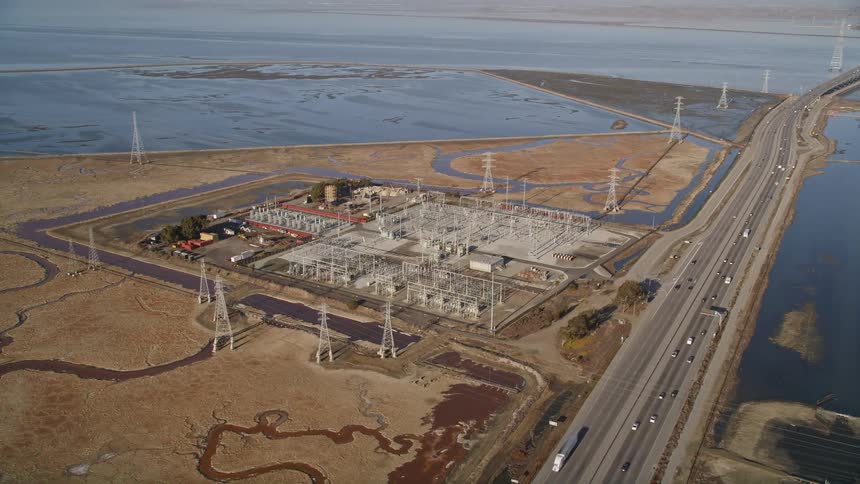 Aerial panorama of an extensive highway that passes through a river channel and next to an electric power station