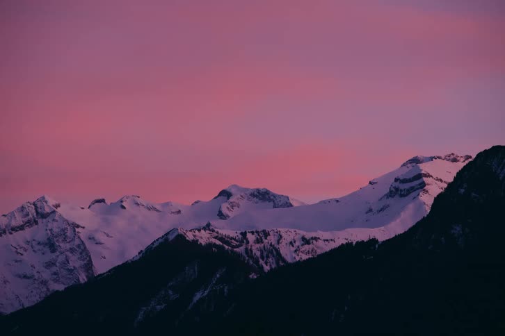 Landscape of mountain ranges with cliffs and covered by snow with a purple sky