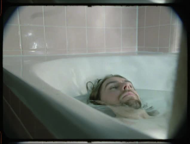 Portrait of a man lying in the bathtub and becoming fully submerged and coming back