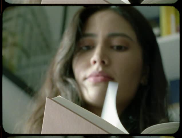 A woman reads a book then glances out the window