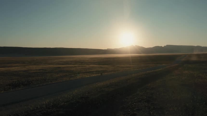 A person is riding their bicycle on the highway at sunrise