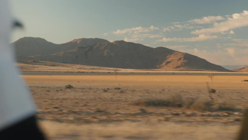 Cyclist cycling in a desert environment with mountains on the horizon