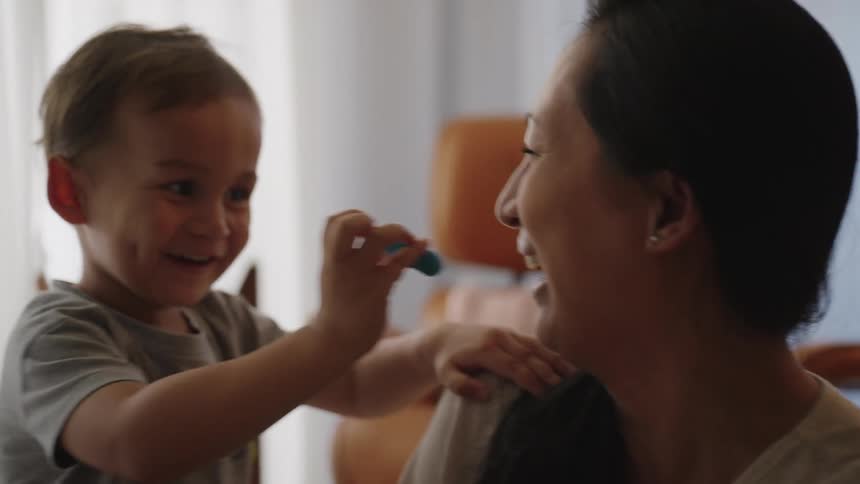 Portrait of mother playing with her little son with modeling clay and smiling a lot