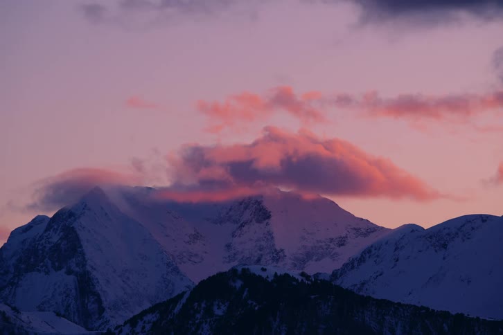 Landscape of mountain ranges covered by snow on a red sky morning