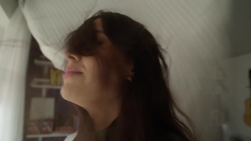 A teenage girls face being beaten by a wind blown curtain