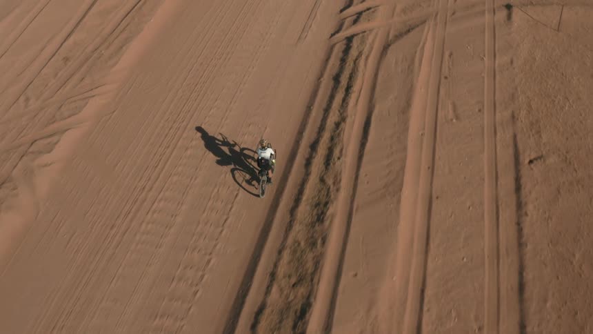Top view of a person pedaling bicycle in desert terrain during daytime